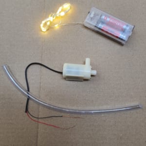 Máy bơm chìm mini sử dụng pin kết hợp với đèn led dây, có kèm pin và 30 cm dây dẫn nước